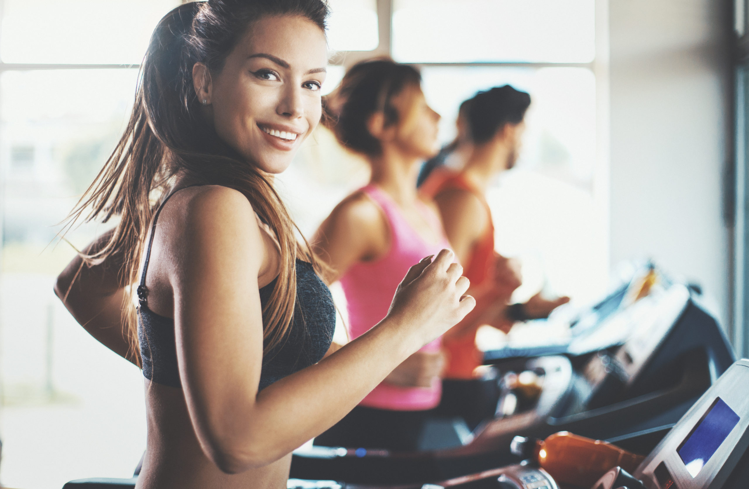 Closeup side view of a late 20's woman doing some cardio workout on a treadmill.