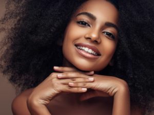 Black-woman-smiling-with-perfict-skin-and-hands-under-face